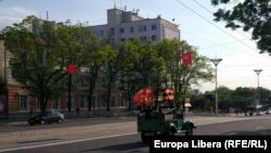 Camionetă militară pe o stradă din Tiraspol cu drapelul URSS și așa-numita panglică a Sfântului Gheorghe, promovată în ultimii ani de Rusia drept simbol al Zilei Victoriei