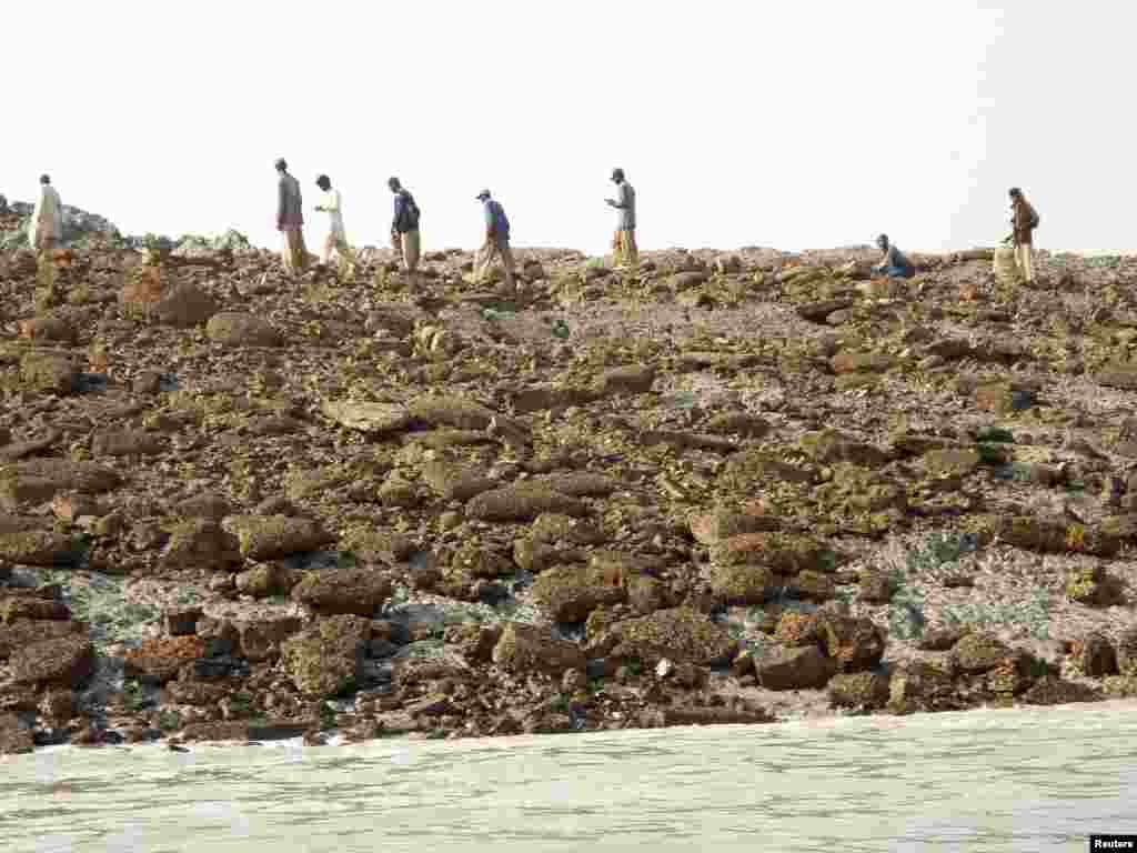 People walk on an island that rose from the sea following an earthquake, off Pakistan's Gwadar coastline in the Arabian Sea. (Reuters)