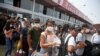 Peru - People wearing face masks wait to board a bus at a bus station after Peru's government deployed military personnel to block major roads, as the country rolled out a 15-day state of emergency to slow the spread of coronavirus disease (COVID-19), in 