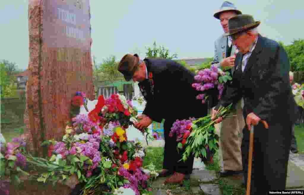 Andrei Găină (dreapta, cu baston) depunânnd flori la monumentul ostașilor sovietici din satul său, 90 mai 2007.