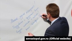 Дмитро Овсянников підписує вітальну листівку. Севастополь, 8 березня 2017 року
