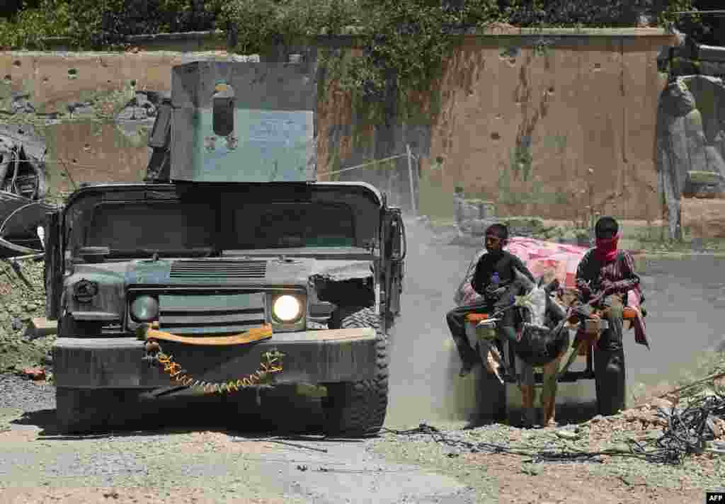 An Iraqi military vehicle passes displaced Iraqi boys who were returning to their homes in western Mosul's Oreibi neighborhood after government forces retook control of the area from the Islamic State militant group. (AFP/Ahmad al-Rubaye)