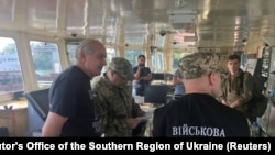 A handout photo obtained by Reuters shows Ukrainian security-service officers and a crew member (left) of the Russian tanker.