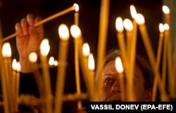 Жена запалва свещ по време на коледна литургия в катедралата 