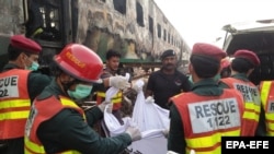 Спасатели выносят тела погибших при пожаре в пассажирском поезде вблизи пакистанского города Рахим Яр Хан. 31 октября 2019 года.
