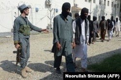 A member of the Afghan security forces escorts alleged Islamic State fighters and Taliban being presented to the media at the police headquarters in Jalalabad on October 3.