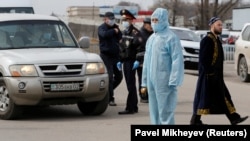 Человек в защитном костюме на блокпосту на границе Алматы и Алматинской области. 
