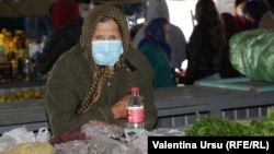 Moldova - Nisporeni, market, people, old woman with mask, selling greens