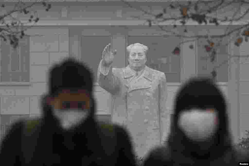 People in surgical masks against pollution walk in front of a statue of late Chinese leader Mao Zedong during a hazy day at a university in downtown Shanghai. (Reuters/Aly Song)