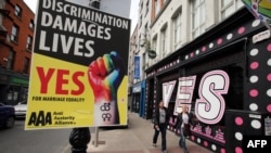 Пешеходы идут рядом с плакатом в поддержку однополых браков. Дублин, 21 мая 2015 года.