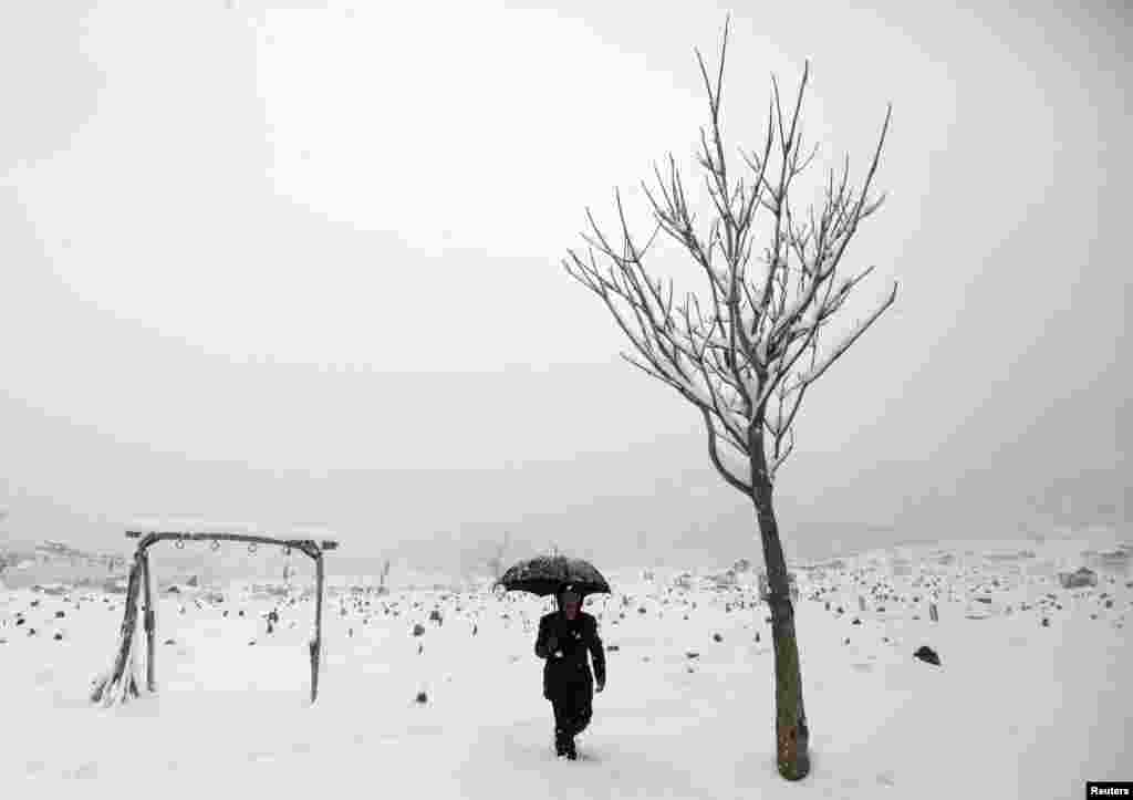 زنی افغان در حال گذر از روی برف ها در کابل
