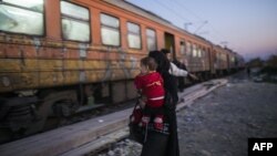 A woman and her child prepare to board a train heading to Serbia after crossing the Greek-Macedonian border on November 12, 2015.