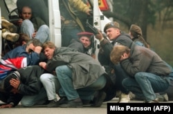 A Bosnian soldier returns fire on April 6, 1992, in downtown Sarajevo as he and civilians come under fire.