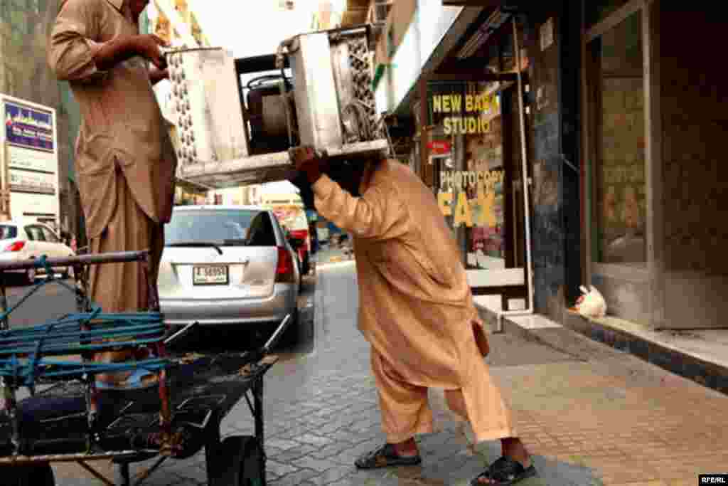 Men carry heavy equipment on a Dubai street.