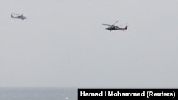 AT SEA -- A Iranian Revolutionary Guard boat is seen near the U.S. aircraft carrier, USS George H. W. Bush while transiting Straits of Hormuz as U.S. Navy helicopters hover over it during early hours, March 21, 2017