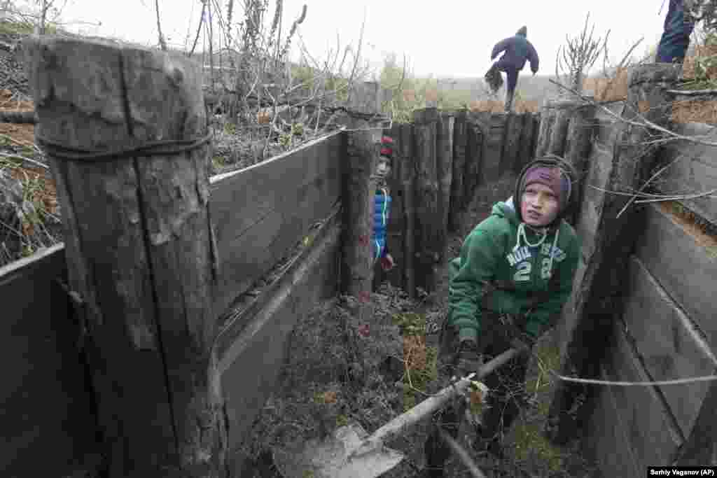 Children from an orphanage volunteer to help city defenders strengthen trenches of Ukrainian Army positions near the village of Rybatske, 25 kilometers from Mariupol. Ukrainian lawmakers voted to approve a presidential request for the introduction of martial law in the country following an incident in which Russian coast-guard ships fired on Ukrainian Navy vessels and took crew members captive. (AP/Sergei Vaganov)