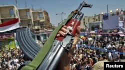 An army officer raises his rifle as he joins antigovernment protesters during a rally demanding the ouster of President Ali Abdullah Saleh in Sanaa today.