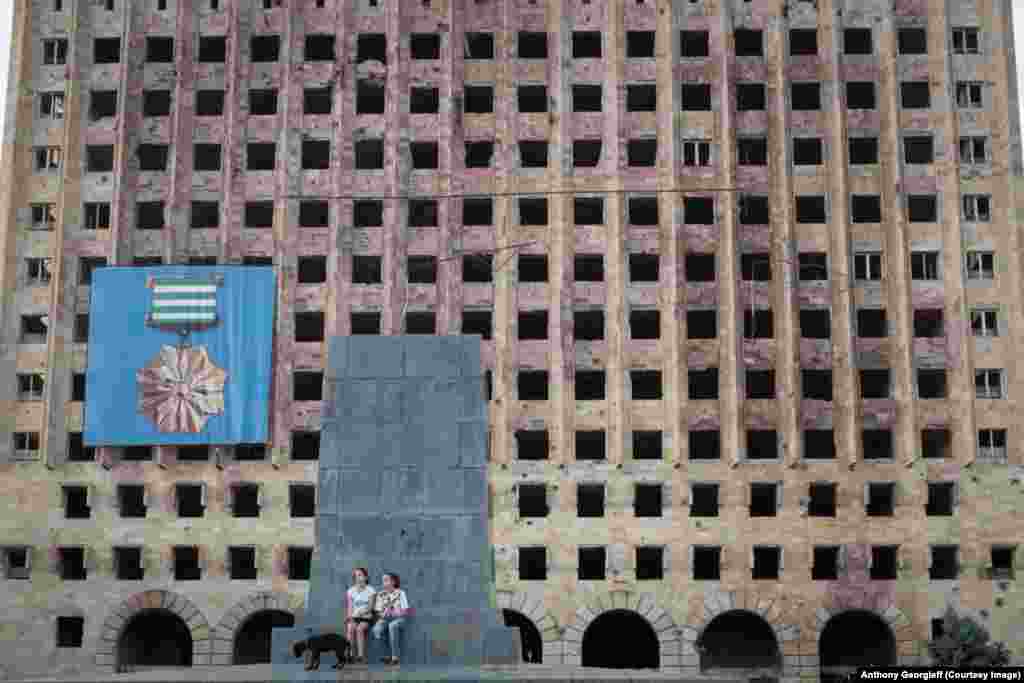 Two girls walk a dog in front of the abandoned Soviet-era government building in downtown Sukhumi. The area was the site of fierce battles in the 1992-1993 conflict.