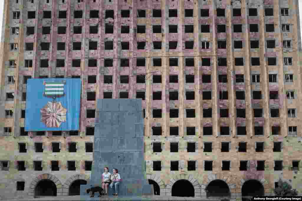 Two girls walk a dog in front of the abandoned Soviet-era government building in downtown Sukhumi. The area was the site of fierce battles in the 1992-1993 conflict. 