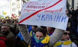 A Ukrainian woman holds a placard denouncing any agreements with the "enemy" during a rally outside the presidential office in Kyiv earlier this month.