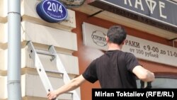 Russia - Labour migrants. The man from Kyrgyzstan washes a window in cafe. Moscow. 27Apr2012