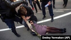 A riot police officer tries to detain a woman during a rally in St. Petersburg on May 1.