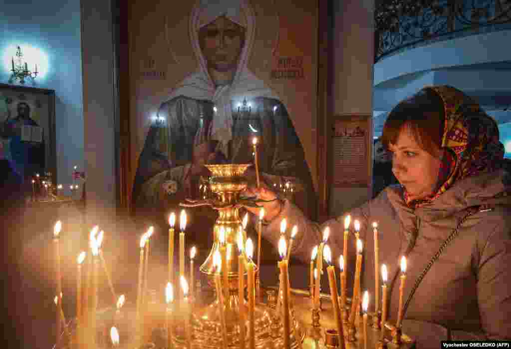 7-nji ýanwar, prowaslaw hristianlaryň Ýakyn Gündogardaky, Orsýetdäki we beýleki ýerlerdäki prowaslaw ybadathalarda Kristmas baýramyny belleýän wagtynda Bişkekdäki ybadathanada şem ýakýan aýal. (AFP/Vyacheslav Oseledko)