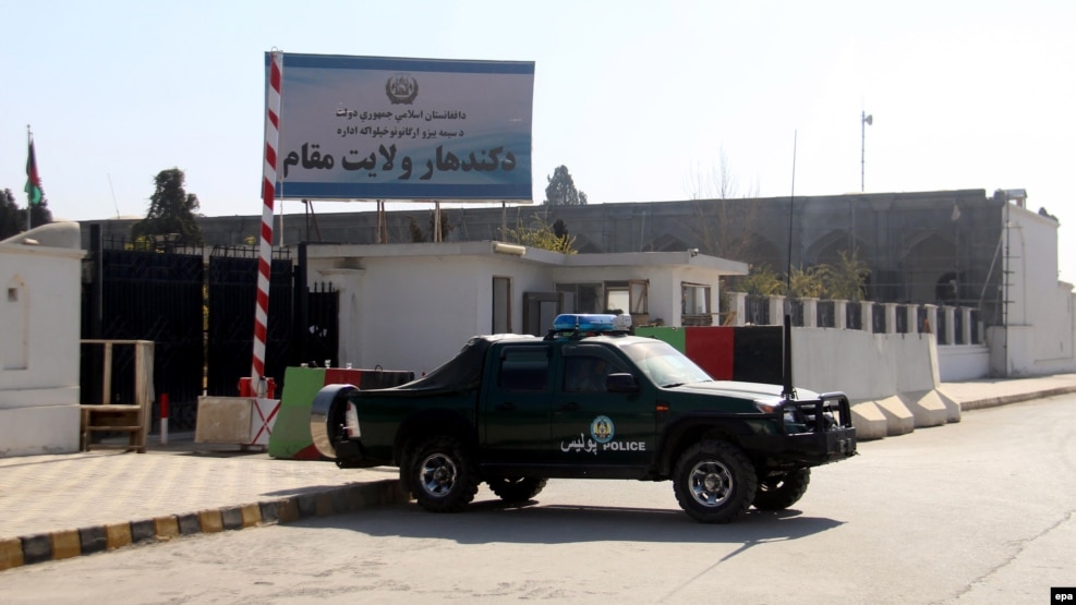 Afghan security officials stand guard outside the government guesthouse after a bomb blast in Kandahar.