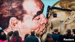 Artist Dmitry Vrubel touches up his famous mural in Berlin in April 2014. 