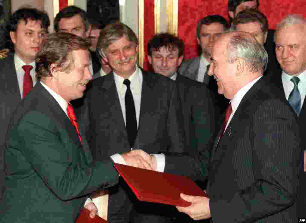 Czechoslovak President Vaclav Havel shakes hands with Gorbachev as they exchange documents on the withdrawal of Soviet troops in Moscow on February 26, 1990.