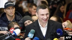 With his brother Vladimir in the background, Kyiv Mayor Vitali Klitschko speaks to the media after casting his ballot during the second round of the municipal election in Kyiv. 