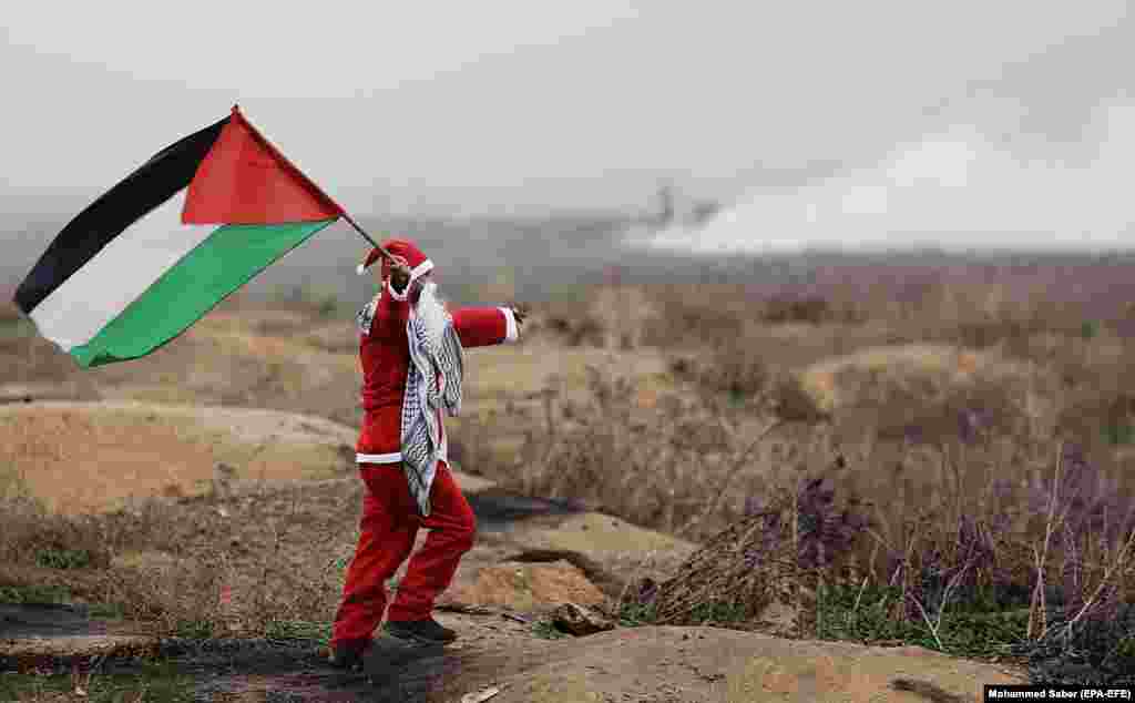 A Palestinian protester dressed as Santa Claus waves a Palestinian flag during clashes following protests against U.S. President Trump's decision to recognize Jerusalem as the capital of Israel. (epa-EFE/Mohammed Saber)