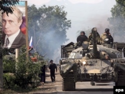 Ресей танкілері сол кездегі Ресей премьері Владимир Путин суретінің қасынан өтіп барады. Оңтүстік Осетия, Цхинвали, 20 тамыз 2008 жыл.