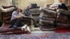 In this Aug. 10, 2015 file photo, Iranian merchants wait for customers at a carpet shop in Tehran's old, main bazaar, Iran.