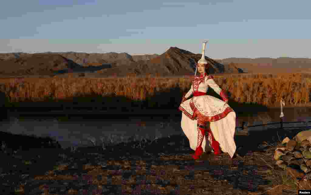 Model Choigana Kertek, dressed in a traditional costume, performs at sunset on the bank of the Yenisei River outside the village of Ust-Elegest in the Tuva region of southern Siberia. (Reuters/Ilya Naymushin)