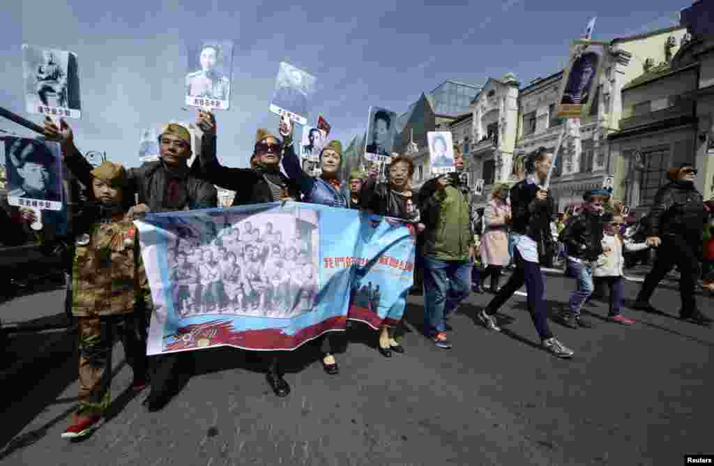 People of the Chinese province of Heilongjiang hold pictures of their relatives who fought during World War II as they take part in an Immortal Regiment march during Victory Day celebrations in the far eastern Russian city of Vladivostok on May 9. (Reuters/Yury Maltsev)