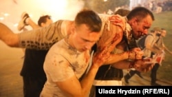 Демонстранти виносять колегу, пораненого в сутичці з силовиками в Мінську після закриття дільниць на президентських виборах 9 листопада 2020 року