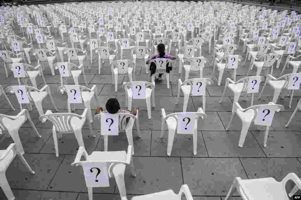 Children sit in chairs covered with question marks displayed in Pristina, Kosovo, on August 30 as part of the International Day of the Disappeared. (AFP/Armend Nimani)