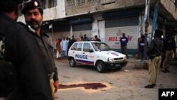 Pakistani police surround a bullet-riddled police vehicle following the attack in Karachi on April 5. A Pakistani commission says ethnic, sectarian, and politically linked violence has killed at least 300 people so far this year in Karachi.