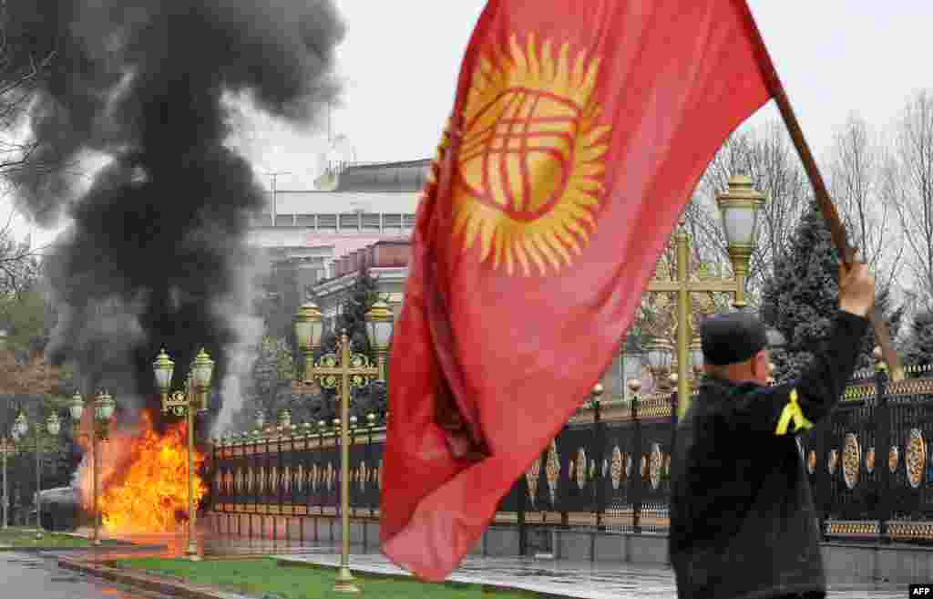 An opposition supporter waves the Kyrgyz flag near the main government building during antigovernment protests in Bishkek on April 7, 2010.