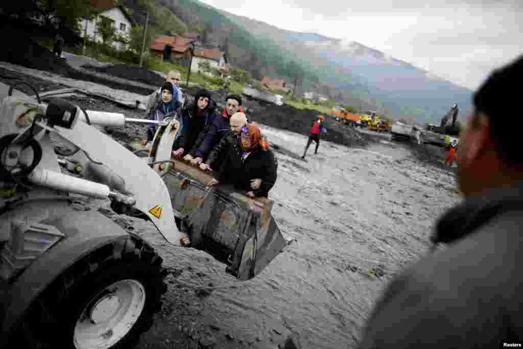 Residents of the flooded Bosnian village of Topcic Polje are evacuated from their homes by backhoe on May 16. (Reuters/Davo Rucic)