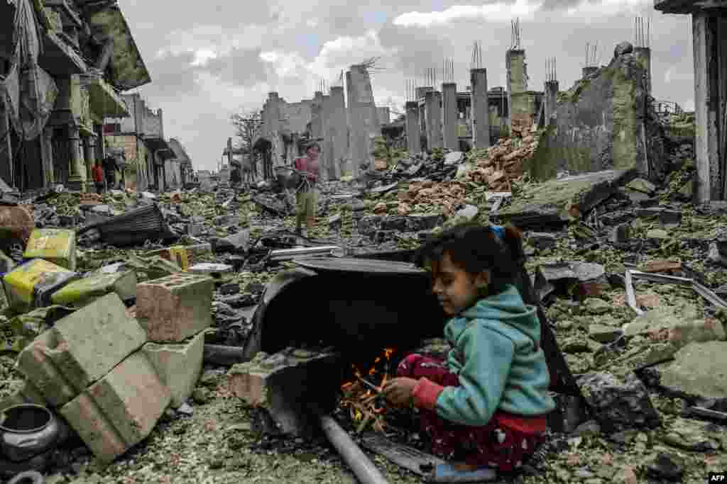 Kurdish Syrian girls are pictured among destroyed buildings in the Syrian Kurdish town of Kobani. (AFP/Yasin Akgul)