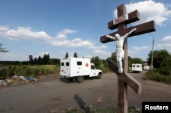 Ambulances are seen near an Orthodox crucifix as Dutch and Australian forensic experts continued recovery work at the site of the downed Malaysian airliner MH17, near the village of Rozsypne, on August 4.