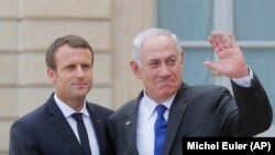 French President Emmanuel Macron, left, shake hands with Israeli Prime Minister Benjamin Netanyahu as he waves waves good-bye to the media after a meeting at the Elysee Palace in Paris, France, Sunday, July 16, 2017.