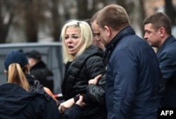 Policemen hold Maria Maksakova, Voronenkov's wife, as she reacts at the scene of her husband's killing.