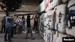 Activists attempt to remove a block from a barrier wall blocking passage to the parliament near Tahrir square in Cairo, 10Jul2012