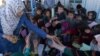 БҰҰ-ның босқындар ісі жөніндегі агенттігі өкілі балаларға қаламсап таратып жатыр. Ауғанстан, Кабул маңы, БҰҰ босқындар лагері, 27 қыркүйек 2016 жыл. (Көрнекі сурет)
