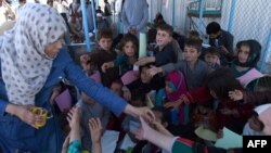 FILE: A UN aid worker distributes pens to Afghan refugee children upon their return to Afghanistan from Pakistan.