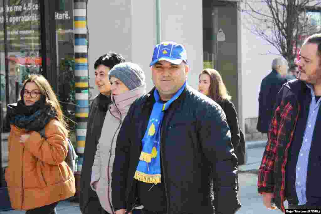 Një burrë ka veshur një kapelë dhe shall me simbolet shtetërore të Kosovës 