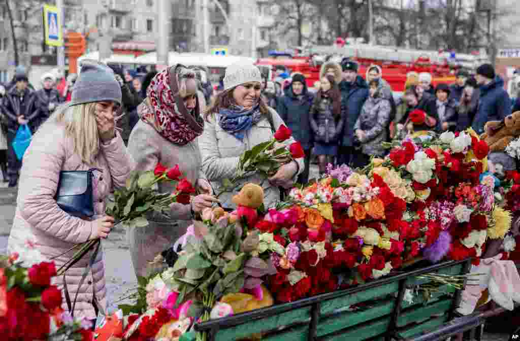 People lay flowers for the victims at a makeshift memorial near the shopping center.